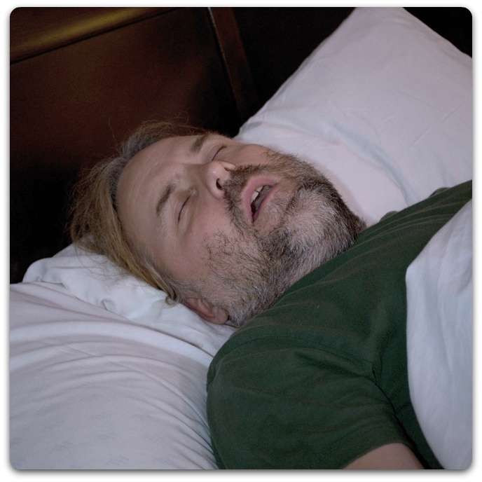 Man in bed with sleep apnea snoring